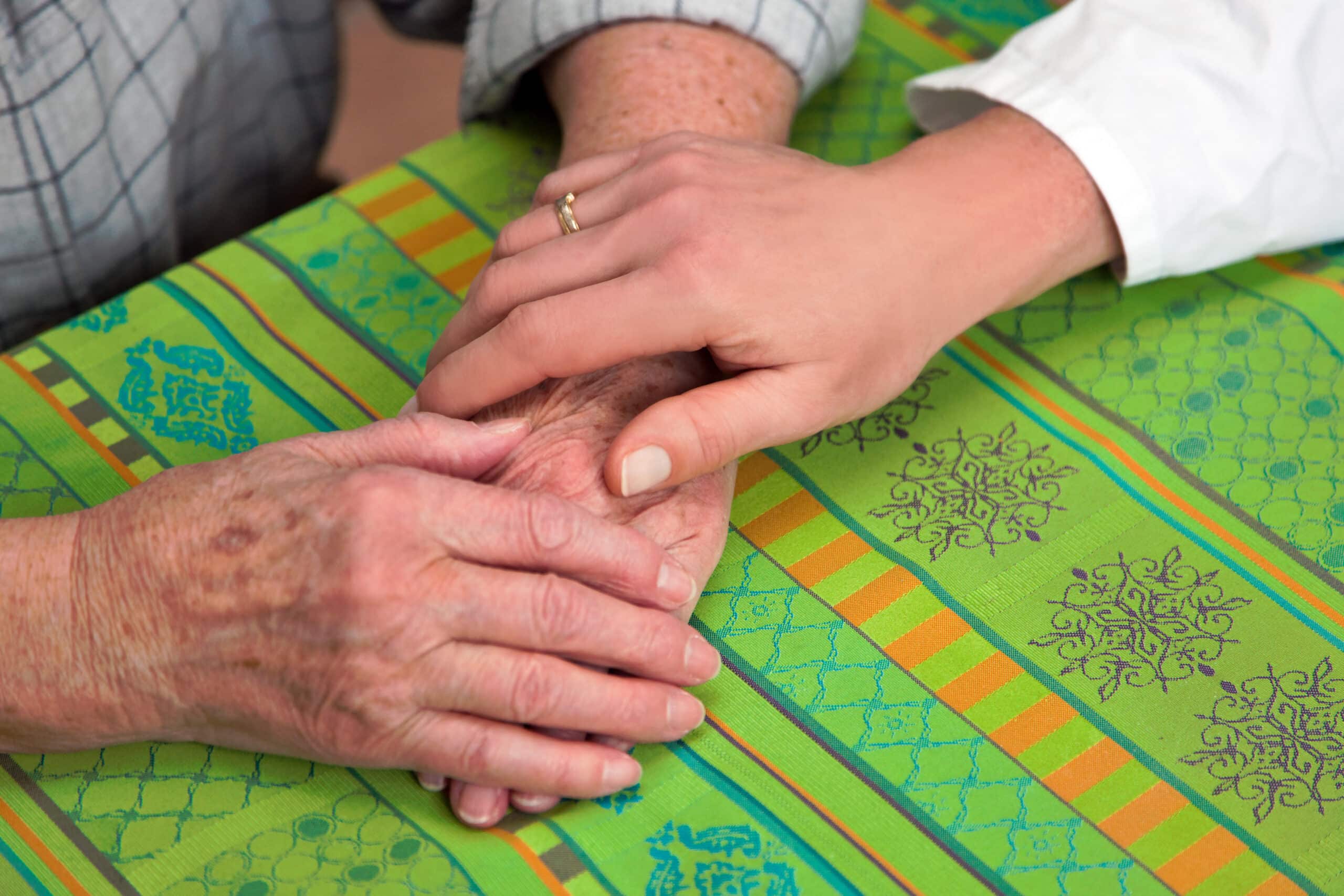 Eine Pflegekraft hält die Hände einer Seniorin